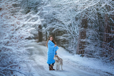 Full length of woman with dog on snow