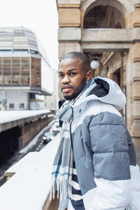 Young african man on street, snow winter season, city portrait