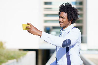 Side view of young man holding smart phone