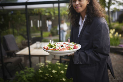 Smiling woman holding food on plate