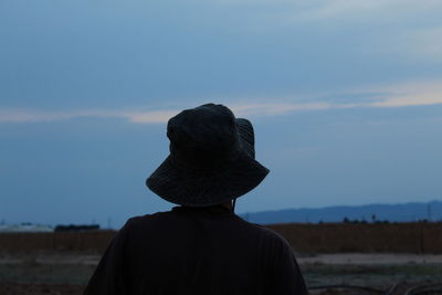 Rear view of man standing on rock against sky