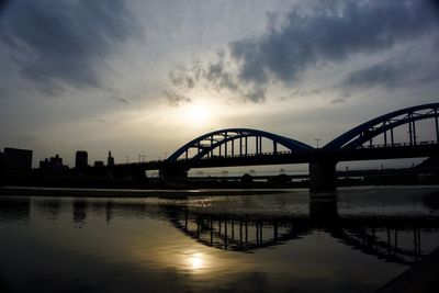 Bridge over river against sky during sunset