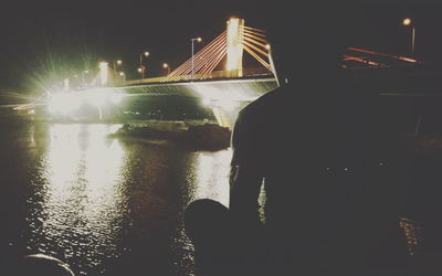 Man by illuminated bridge against sky at night