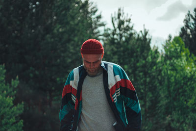 Young man standing against trees in forest