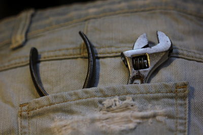 Close-up of wrench and plier on person back pocket