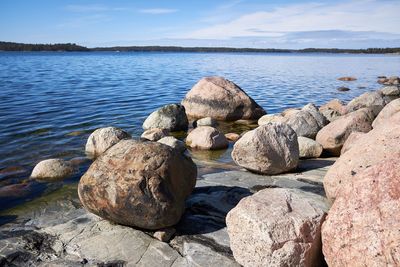 Rocks on shore by sea against sky