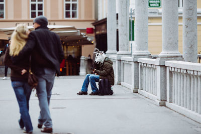 Rear view of people walking on sidewalk in city