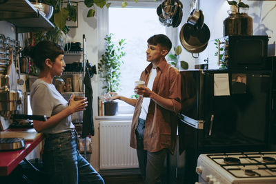 Young male and female freelancers discussing in kitchen during coffee break at home office