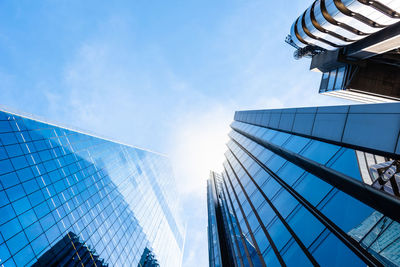 Low angle view of office buildings in the city of london against blue sky.