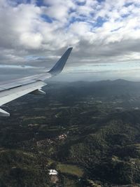 Aerial view of airplane flying over landscape against sky