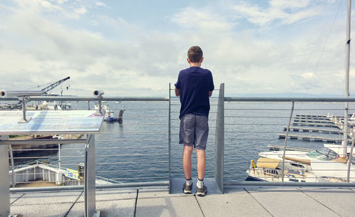 Rear view of man standing by sea against sky