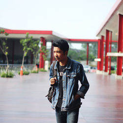 Young man looking away while standing outdoors