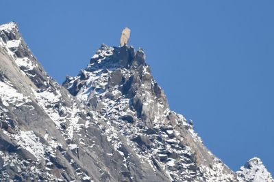 Low angle view of snowcapped mountain against blue sky