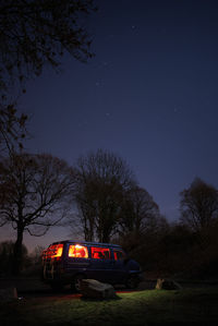 Car on road amidst trees against sky at night