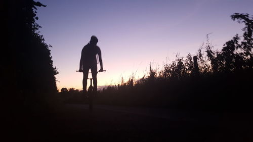 Silhouette people standing on grassy field against clear sky