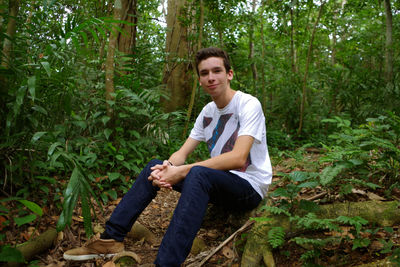 Portrait of a young man sitting in forest