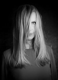 Portrait of young woman standing against black background