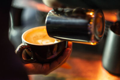 Close-up of hand pouring coffee in cup