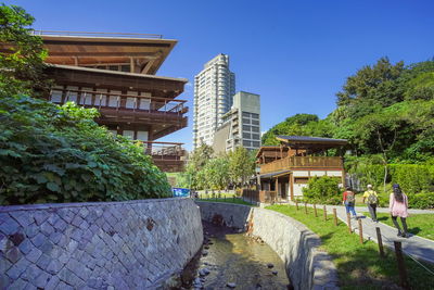 Bridge over canal by buildings against clear blue sky