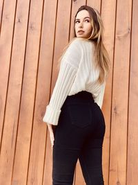 Portrait of young woman standing against wall