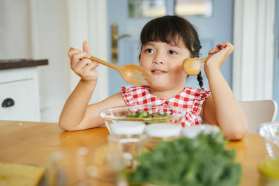 Cute girl eating salad at home