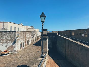 Street light by building against blue sky