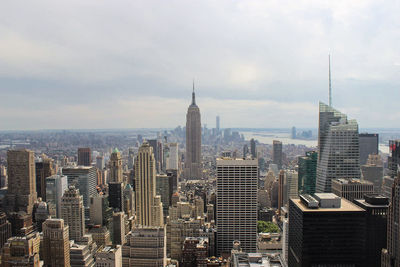 Modern buildings against cloudy sky in city on sunny day