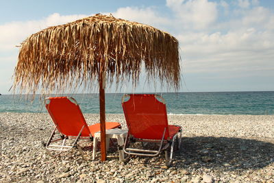 Deck chairs on beach against sky