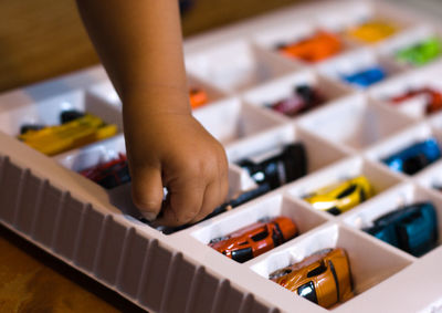 Cropped hand of child removing toy car from box