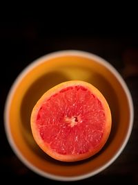 Close-up of fruits in plate against black background