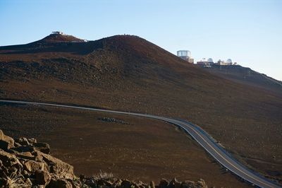 Scenic view of road by mountains against clear sky