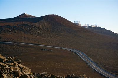 Scenic view of road by volcanic mountains against clear sky