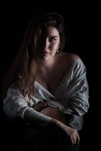 Portrait of young woman against black background