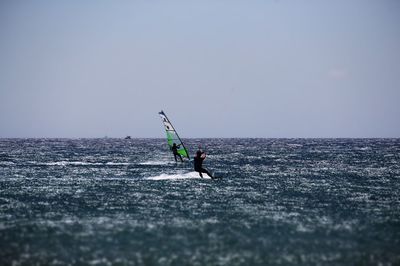 Man surfing on sea against clear sky