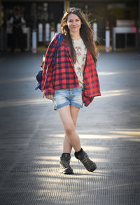 Portrait of young woman standing on footpath