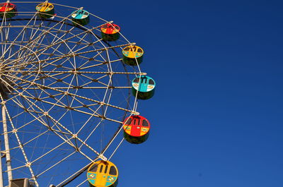 Low angle view of ferris wheel against clear blue sky