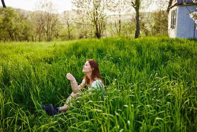 Rear view of woman sitting on grassy field