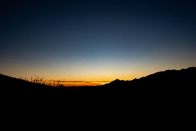 Silhouette landscape against clear sky during sunset