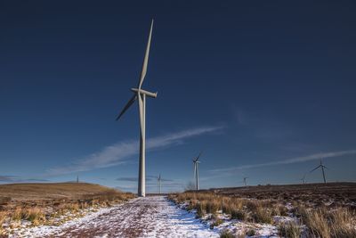 Windmills on landscape against sky