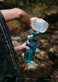 Close-up of man filtering water from one bottle to another
