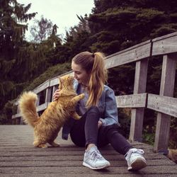 Young woman with dog against trees