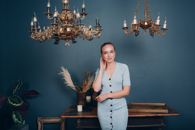 Portrait of smiling young woman standing against illuminated wall