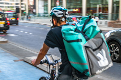 Rear view of man riding bicycle on street in city