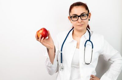 Portrait of young man holding apple against white background
