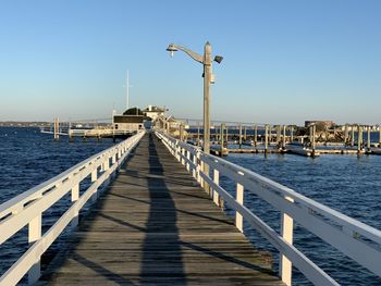 Pier over sea against clear blue sky