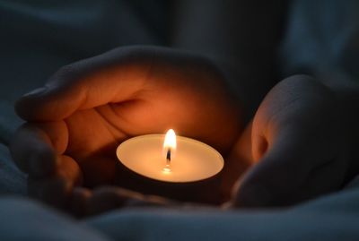 Close-up of hand holding burning candle