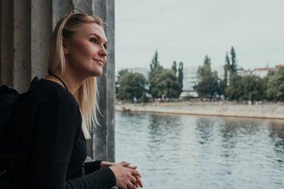 Portrait of beautiful young woman looking away against trees