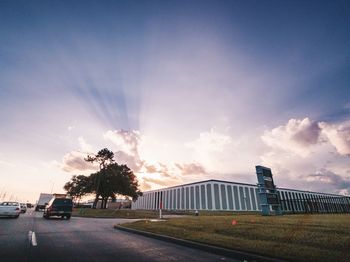 Road by city against sky during sunset