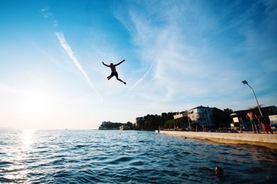 Man jumping over sea against sky