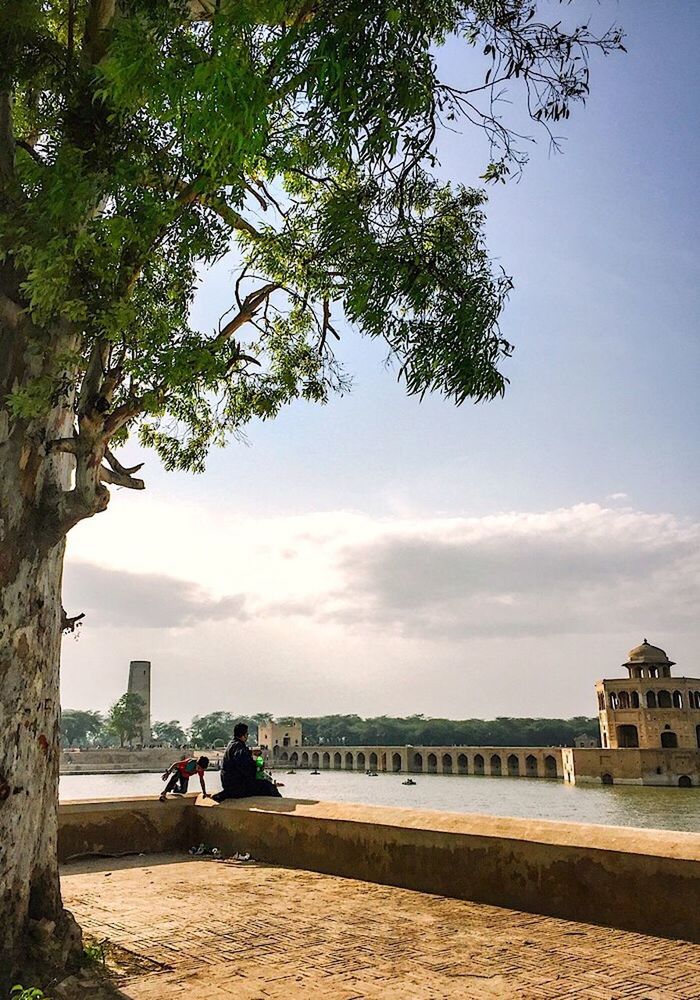 tree, day, built structure, water, sky, architecture, building exterior, real people, beach, outdoors, sea, men, nature, travel destinations, beauty in nature, sand, growth, sitting, women, people